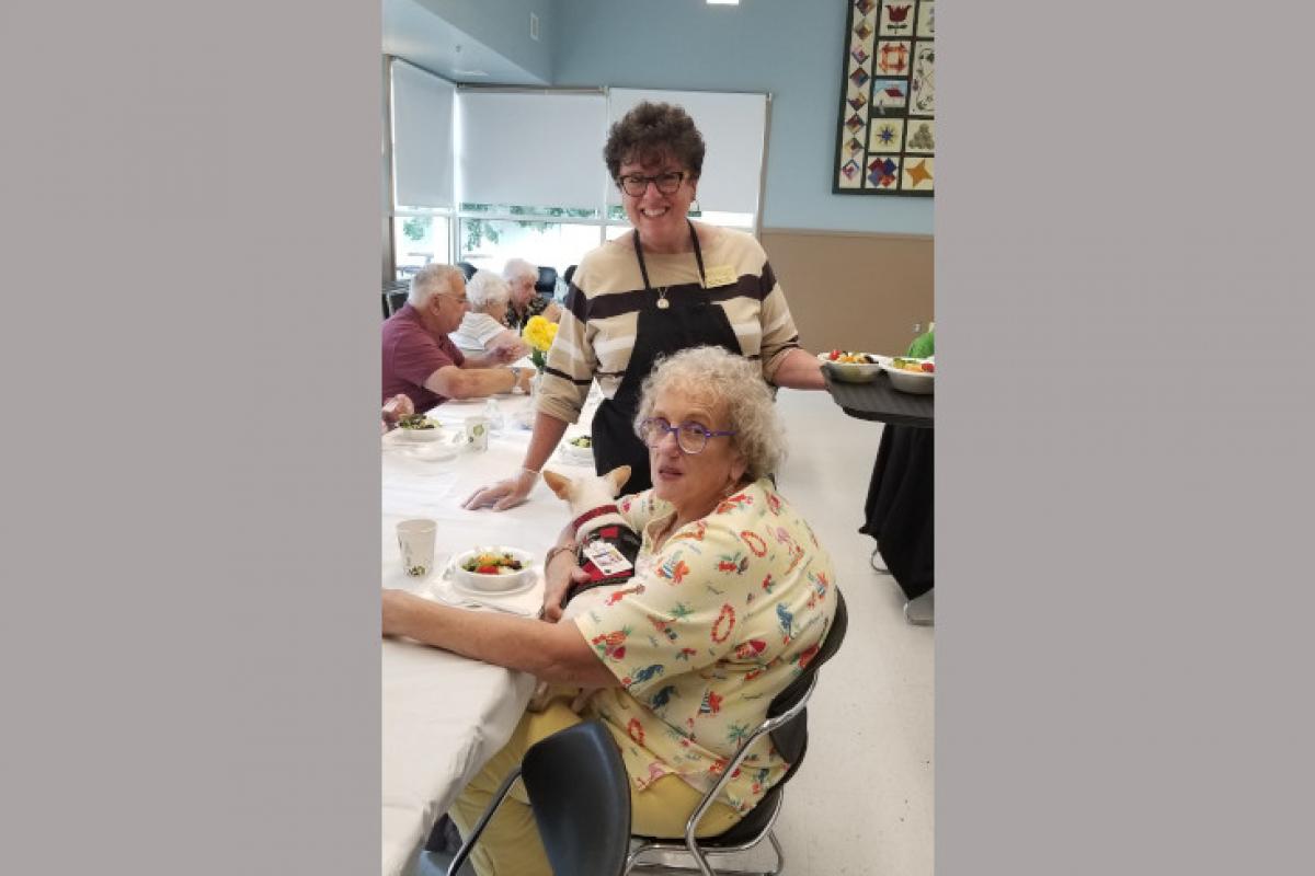 Woman Seated at Table Holding Dog