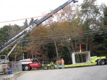 Cement Block on Trailer Being Strapped to Crane