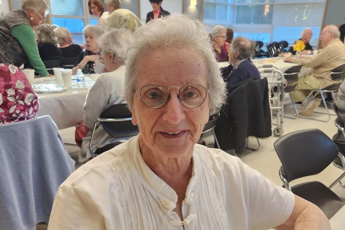 Woman Seated with Other Attendees in Background