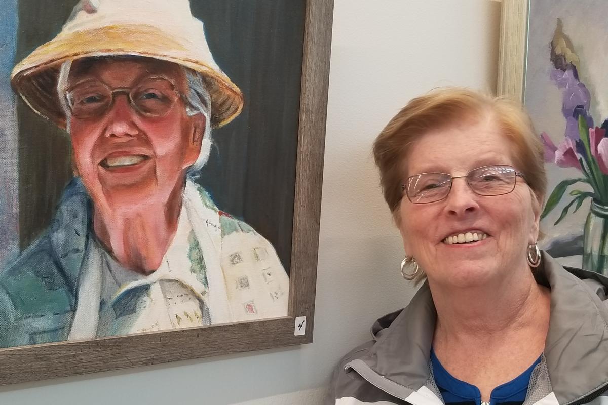 Woman Smiling Next to Painting on the Wall