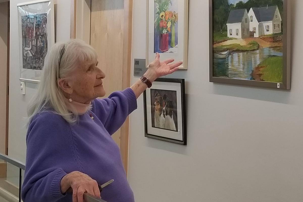 Woman Gesturing at Paintings on the Wall