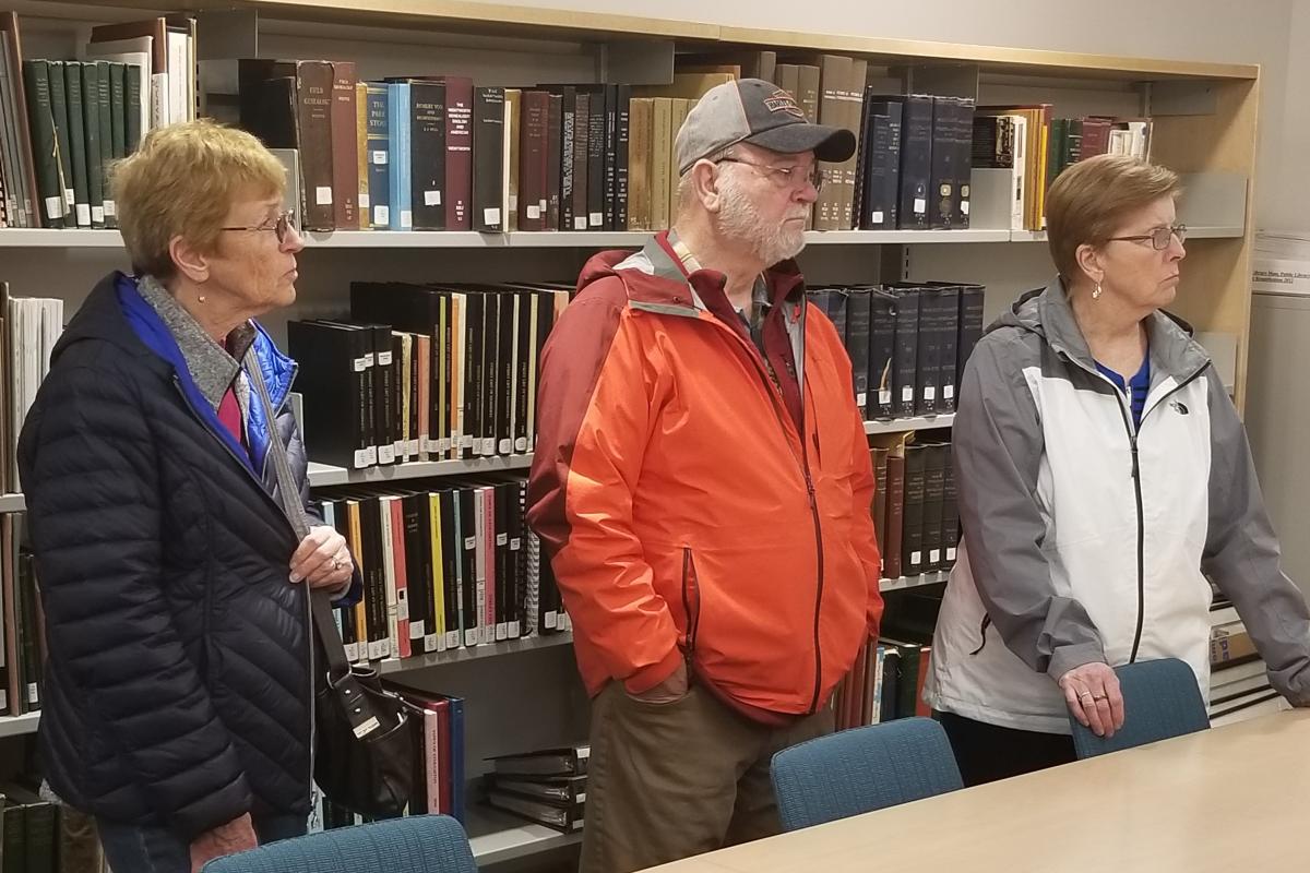 Three People in Front of Book Shelf
